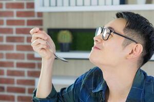 Portrait of a happy young man tasting food. Side view. Space for text photo