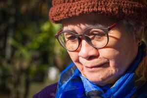 Portrait of a happy senior woman smiling and looking down while standing outdoors. Space for text. Concept of aged people and healthcare photo