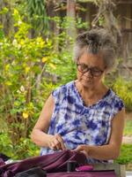 An elderly woman's hands using needle and thread to mend a pant photo