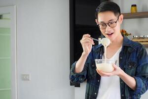 Young man cook wearing casual cloth in the kitchen. Young man worker uses whisk and bowl for making mixing ingredients in a bowl. Kitchen tools and cooking concept photo