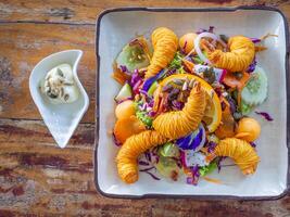 Fresco Fruta ensalada y camarones frito con espaguetis en un plato en un de madera mesa. vistoso con selectivo enfocar. parte superior vista. concepto de salud comidas foto