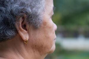 Side view of face senior woman looking away while standing outdoors. Space for text. Concept of aged people and healthcare photo