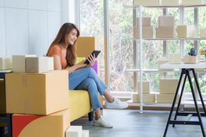 Young businesswoman smiling holding and looking at a tablet while sitting on a sofa in the office. Concept of business and e-commerce photo