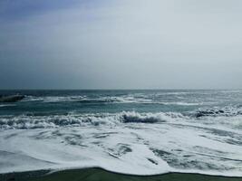 Sea wave surf with white foam. Seascape. Wet sand. photo