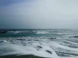 Sea wave surf with white foam. Seascape. Wet sand. photo