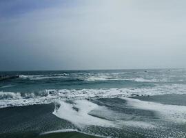 Sea wave surf with white foam. Seascape. Wet sand. photo