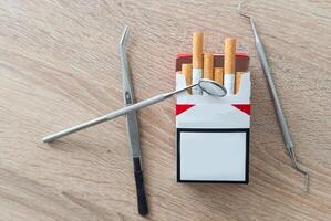 Image of dental tools with cigarettes on the table background photo