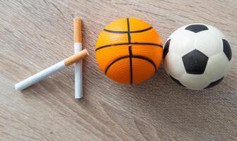 Smoking or sports. Sport ball and pack of cigarettes on table background. Top view photo