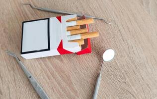 Image of dental tools with cigarettes on the table background photo