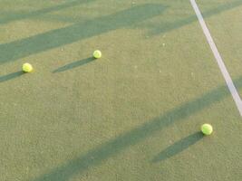 Tennis balls on a outdoor green hard court photo