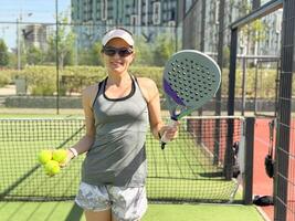 Happy female paddle tennis player during practice on outdoor court. Copy space. photo