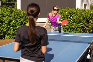 Adult woman instructor teaching girl play table tennis photo