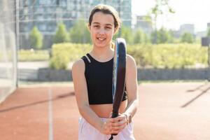 Padel tennis player with racket and ball in hands. Girl athlete with paddle racket on court outdoors. Sport concept. Download a high quality photo for the design of a sports app or web site.