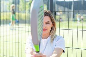 Happy female paddle tennis player during practice on outdoor court looking at camera. Copy space. photo