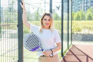 Sportive young girl with racquet playing padel in court. photo