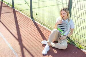 contento hembra paleta tenis jugador durante práctica en al aire libre Corte mirando a cámara. Copiar espacio. foto