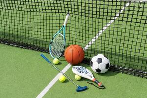 A variety of sports equipment including an american football, a soccer ball, a tennis racket, a tennis ball, and a basketball photo