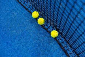 several balls by the net on a blue paddle tennis court photo