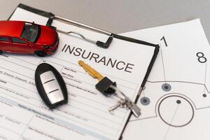 Top view of car insurance claim form with car key and car toy on desk photo