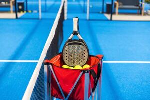 Paddle tennis. Padel racket and ball in front of an outdoor court. photo