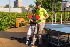 Happy man with his daughter playing ping pong in park photo