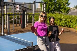 mother and daughter play ping pong in park photo