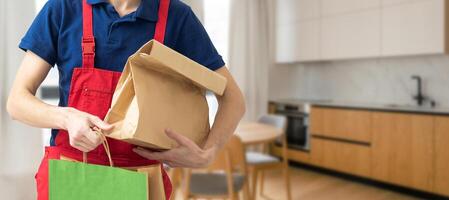 Courier holding paper bags with food, space for text. Delivery service photo