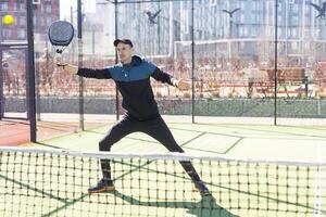 Man playing paddle tennis. Jumping and shooting the ball. photo