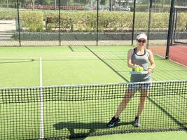 Woman playing padel in a grass padel court indoor - Young sporty woman padel player hitting ball with a racket photo