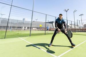 joven padel jugador trenes por atrapando alto pelotas foto