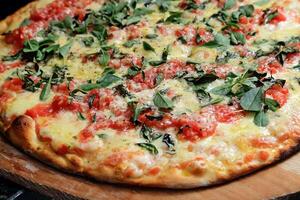 margherita Pizza viniendo fuera de el horno con queso, tomate salsa y albahaca foto