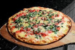 Margherita pizza coming out of the oven with cheese, tomato sauce and basil photo