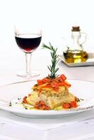 roast cod with chopped tomatoes, peppers and olive oil on plate photo