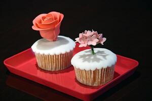 cupcakes with sugar flower decoration on red tray photo