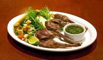 grilled lamb with salad and chimichurri sauce on plate photo