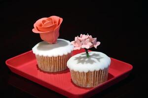 cupcakes with sugar flower decoration on red tray photo