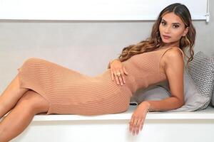 young and beautiful Brazilian model posing in colorful dress and acting with her cell phone photo