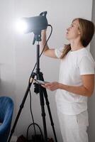 woman maker at work, working on content making, using and controlling light strobe photo