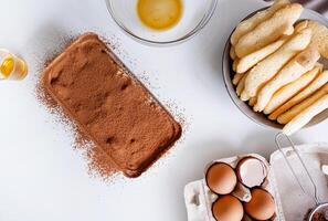 Tiramisu haciendo proceso. italiano postre en frustrar bandeja y ingredientes en cocina mesa foto