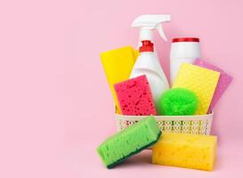 Cleaning service concept. Detergents and cleaners in the basket on the pink background. Close-up. Copy space. Selective focus. photo