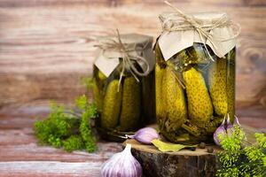 Delicious pickled cucumbers in jars on a wooden table. Close-up. photo