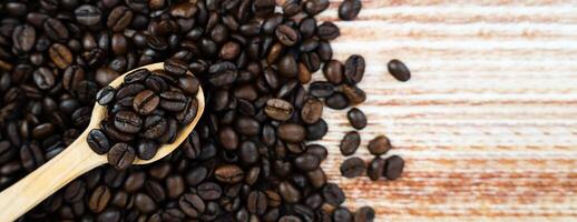 Aromatic natural coffee beans in a spoon on the background of coffee beans. Banner. Top view. Place for text. Selective focus. photo