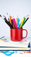 School stationery in a red mug stand on the books. Back to school. Close-up. Selective focus. photo