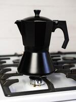 Black geyser coffee maker on the stove at the kitchen. Preparation of natural coffee at home. photo