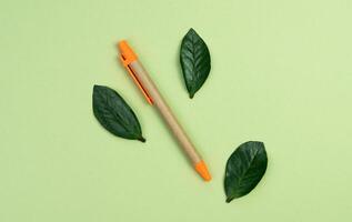 Pen made of eco friendly materials on a green background. Top view. Flatlay. Copy space. photo