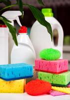 Various detergents and cleaning products, kitchen rags and sponges on the table in the kitchen. Spring cleaning concept. Close-up. Selective focus. photo