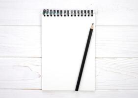 A blank notebook and a pencil on a white wooden background. Flatlay composition. Mockup. Top view. Copy space. photo