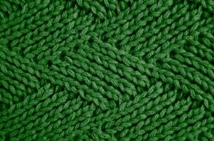 Knitted green wool scarf with a diamond pattern. Abstract background. Close-up. Selective focus. photo