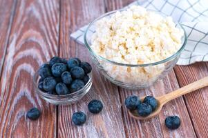 Freshly picked blueberries and homemade cottage cheese on the wooden background. Healthy food concept. Close-up. photo