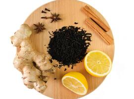 A black dry tea, ginger, lemon and cinnamon isolated on white background. Tea drinking concept. Top view. Close-up. Selective focus. photo